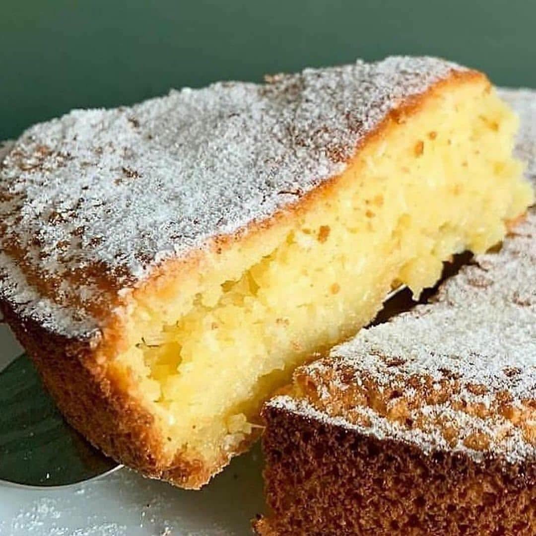 # Seus filhos vão te chamar de rainha depois que você servir esse bolo de mandioca sem farinha Meninas, preparem a vossa melhor forma redonda e liguem já o forno porque a receita de hoje traz aquele sabor inconfundível de fazenda, simplicidade de terra boa e aconchego de cozinha de vó! Sabem aquela fatia alta, com uma crosta douradinha e crocante por fora coberta por uma chuva suave de açúcar e canela, revelando um miolo amarelo-claro tão cremoso, aveludado e húmido que parece quase uma queijadinha nobre a derreter na boca logo na primeira mordida? Pois bem, este bolo de mandioca sem farinha (também conhecido por muitos como bolo de aipim ou macaxeira) é a verdadeira glória da doçaria caseira tradicional. O melhor de tudo é que ele não leva um único grama de farinha de trigo, dispensa processos complicados e aproveita a cremosidade natural da raiz fresca para criar uma textura dos deuses sem esforço! Quero fazer um convite muito animado, carinhoso e cheio de energia a cada uma de vocês: vistam o vosso avental mais bonito, passem um café fresco no coador e venham comigo para a beira da bancada desfrutar deste momento acolhedor! Poucas coisas na doçaria artesanal dão tanto prazer quanto ralar a mandioca fresca, misturar os ingredientes com uma colher e sentir aquele perfume adocicado de coco com manteiga a invadir cada divisão da casa enquanto o forno faz a sua magia. Tenho a certeza absoluta de que, assim que colocarem este bolo fumegante no prato e tirarem a primeira fatia triangular com a espátula, a família inteira vai bater palmas e disputar a última migalha. Venham daí aprender todos os segredos para acertar o ponto da massa, equilibrar a humidade e surpreender toda a gente com o melhor bolo de mandioca da vossa vida! ## Ingredientes do bolo de mandioca sem farinha Para a massa cremosa e aveludada: * 1 kg de mandioca fresca (aipim ou macaxeira) descascada, crua e ralada fininha no ralador ou triturada no processador * 1 lata ou caixinha de leite condensado tradicional (395 g) * 1 chávena e meia de açúcar refinado fino ou açúcar cristal (cerca de 270 g) * 3 ovos médios inteiros biológicos em temperatura ambiente * 3 colheres de sopa bem cheias de manteiga sem sal em ponto de pomada (cerca de 60 g) * 200 ml de leite de coco tradicional de boa qualidade (1 garrafinha) * 1 chávena de leite gordo integral morno (cerca de 240 ml) * 100 g de coco ralado fresco em flocos médios ou coco seco ralado sem açúcar * 50 g de queijo parmesão ralado fino ou queijo de minas curado (o grande segredo de mestre para criar aquele contraste rústico queijudo irresistível) * 1 colher de sopa de fermento químico em pó para bolos * 1 pitadinha generosa de sal marinho fino (para acentuar os açúcares naturais da raiz) Para a finalização e polvilho: * 2 colheres de sopa de açúcar de confeiteiro misturadas com 1 colher de café de canela em pó (para polvilhar sobre o bolo já assado e criar o acabamento visual da foto) * 1 colher de sopa de manteiga sem sal e açúcar fino para untar a forma Para elaborar este clássico acolhedor da pastelaria brasileira de raiz, os utensílios utilizados são muito práticos e comuns em qualquer lar: um ralador manual de quatro faces ou processador de alimentos para ralar a mandioca crua sem esforço, uma tigela espaçosa para misturar os ingredientes à mão com uma colher de pau ou espátula de silicone resistente, uma peneira fina para polvilhar o açúcar de acabamento no final e uma forma redonda de aro liso ou fundo falso (com cerca de 22 a 24 centímetros de diâmetro e bordas de 5 a 6 cm de altura) untada com manteiga e polvilhada com açúcar fino para caramelizar a lateral. O tempo de trabalho ativo com as mãos é de cerca de 15 a 20 minutos para descascar, ralar a mandioca e misturar a massa, somando-se aproximadamente 50 a 55 minutos de cozedura no forno a temperatura média-baixa para dourar bem a superfície e cozer o centro cremoso. A receita rende um bolo robusto e pesado de cerca de 12 a 14 fatias triangulares fartas, perfeito para reunir a criançada e a família toda à volta da mesa com pura fartura. ## Modo de preparo da receita 1. Comece pelo tratamento da mandioca: descasque a raiz sob água corrente, retire o cordão fibroso central duro e rale toda a polpa crua na face fina do ralador manual de legumes (ou passe no processador de alimentos acionando no modo triturador até obter uma pasta fina com pequenos grânulos). Não precisa de espremer o caldo da mandioca; essa humidade natural é o que confere a cremosidade semelhante a pudim no miolo do bolo! 2. Pré-aqueça o forno a 180 graus. Unte a forma redonda generosamente com manteiga e polvilhe com açúcar refinado em toda a base e laterais, sacudindo o excesso; o açúcar vai caramelizar suavemente no forno, formando aquela casquinha dourada estaladiça nas bordas. 3. Numa tigela ampla, coloque os 3 ovos inteiros, a manteiga amolecida e o açúcar refinado. Bata com uma vara de arames (fouet) ou colher de pau durante cerca de 2 a 3 minutos até obter uma emulsão esbranquiçada e aveludada. 4. Adicione o leite condensado, a garrafinha de leite de coco e o leite integral morno. Misture energeticamente para incorporar todos os líquidos. 5. Acrescente a mandioca ralada crua, o coco ralado em flocos, o queijo parmesão de boa cura e a pitadinha de sal fino. 6. Misture tudo muito bem com a colher de pau em movimentos circulares lentos de baixo para cima, garantindo que a mandioca se espalhe uniformemente por todo o creme lácteo sem criar pelotes compactos. A consistência da massa é densa e ligeiramente líquida, o que é absolutamente correto por não conter trigo. 7. Adicione a colher de sopa de fermento químico em pó por último e envolva suavemente até que o pó desapareça na mistura. 8. Verta a massa com cuidado na forma redonda preparada, alisando suavemente o topo com uma espátula. 9. Leve ao forno previamente aquecido a 180 graus durante cerca de 50 a 55 minutos. 10. O ponto exato de tirar do forno é quando o topo estiver com uma tonalidade castanho-dourada uniforme, as bordas firmes e tostadinhas e, ao espetar um palito ou ponta de faca no centro, ele sair húmido, mas limpo de massa líquida crua. 11. Retire o bolo do forno e coloque-o sobre uma bancada para arrefecer durante cerca de 30 a 40 minutos. Nunca tente cortar ou desenformar este bolo a ferver, pois a mandioca precisa de assentar o seu amido morno para firmar a fatia sem esfarelar nem quebrar. 12. Com o bolo morno ou já em temperatura ambiente, coloque o açúcar de confeiteiro e a canela numa peneira pequena e polvilhe delicadamente por toda a superfície superior, criando aquela fina camada branca rendilhada sobre a crosta tostada. 13. Corte com uma espátula afiada em fatias triangulares altas e sirva para a família com muito orgulho! No último domingo à tarde, decidi preparar este bolo de mandioca na minha forma redonda tradicional para receber os meus sobrinhos e as crianças da rua que vinham brincar no jardim. O meu marido estava deitado na rede da varanda a fingir que estava compenetrado a ver um documentário histórico na televisão e garantiu em tom sério que não ia tocar num doce sequer porque o almoço de domingo tinha sido farto e ele precisava de manter a disciplina. Pois bem, bastou o bolo entrar nos últimos dez minutos de forno para o cheiro adocicado de mandioca tostada com coco e queijo começar a soprar pela janela da copa com força irresistível! Meninas, as crianças pararam a brincadeira de imediato, entraram na cozinha em fila indiana guiadas pelo aroma e o meu marido veio logo atrás a acelerar o passo a fingir que vinha apenas ajudar a supervisionar os miúdos! Assim que passei a espátula no bolo morno polvilhado com açúcar e ergui a primeira fatia triangular mostrando aquele centro úmido e brilhante a fumegar com delicadeza, os olhos do homem quase saltaram das órbitas! Ele passou à frente das crianças com a maior cara de pau, pegou no pratinho com a fatia, deu a primeira dentada de olhos fechados e soltou um gemido de puro prazer! As crianças começaram a rir da pressa dele e gritaram em coro que a tia era a rainha da cozinha, enquanto o meu marido limpava o queixo salpicado de canela e dizia que a raiz de mandioca era energia pura dos deuses e que comer duas fatias seguidas era indispensável para ele ter forças de continuar deitado na rede até ao anoitecer! ## Acompanhamento perfeito: Calda rústica de melado de cana com gengibre fresco Para quem ama criar aquele casamento sublime entre a rusticidade da raiz de mandioca e um toque exótico marcante, esta calda morna servida em fio ao lado da fatia cria uma experiência digna de fazenda nobre: * 1 chávena de melado de cana puro ou melaço artesanal * Meia chávena de água filtrada * 1 colher de chá de gengibre fresco ralado fininho * 1 casca fina de limão-cravo ou limão tahiti * 1 cravinho-da-índia Num tachinho pequeno em lume brando, junte o melado de cana, a água, o gengibre ralado, a casca de limão e o cravinho. Deixe ferver suavemente durante cerca de 4 a 5 minutos, mexendo com uma colher de pau apenas até o melaço se fundir com a água e formar uma calda aveludada, brilhante e ligeiramente reduzida. Desligue o lume e retire a casca de limão e o cravinho. Sirva morno numa molheira ao lado do prato do bolo. Quando cada pessoa deita um fio desta calda escura e perfumada sobre a fatia amarela e cremosa de mandioca, a picância aromática do gengibre corta a untuosidade da manteiga e do queijo com uma harmonia tão espetacular que transforma o lanche num momento de pura celebração dos sabores da terra! ## Sugestões de ocasiões e formas de servir A imponência deste bolo sem farinha adapta-se com maestria a diferentes celebrações e encontros do nosso quotidiano: * Lanches de domingo à tarde e café colonial: Servido fatiado numa tábua redonda de madeira no centro da mesa, acompanhado de fatias de queijo coalho fresco na chapa, manteiga de garrafa e café passado na hora no coador de pano. * Festas juninas e comemorações típicas de São João: O bolo de aipim é uma das grandes estrelas da mesa caipira ao lado da pamonha, do cuscuz e do bolo de milho verde, sendo sempre dos primeiros pratos a esgotar completamente na travessa. * Sobremesa quente com sorvete: Aqueça a fatia no micro-ondas por 15 a 20 segundos e sirva acompanhada de uma bola generosa de sorvete de tapioca, canela ou nata fresca; o contraste da massa morna e densa com o creme gelado é de outro mundo. * Lanches escolares e pré-treinos funcionais: Por não levar farinha de trigo refinada e ser rico em amido resistente e carboidratos complexos da mandioca, é uma fonte excelente de energia sustentada para crianças e adultos que praticam desporto. ## Versão saudável: Bolo funcional de mandioca com biomassa e açúcar de coco Se procura uma opção rica em fibras de digestão lenta, sem açúcares refinados, livre de glúten e sem lactose sem perder a textura aveludada e cremosa da raiz, esta adaptação funcional é maravilhosa: Ingredientes funcionais: * 1 kg de mandioca biológica crua ralada bem fininha * 3 ovos caipiras biológicos inteiros * 200 ml de leite de coco caseiro concentrado sem conservantes artificiais * Meia chávena de bebida vegetal de amêndoas ou aveia morna * Três quartos de chávena de açúcar de coco, eritritol em pó ou adoçante natural xilitol * 3 colheres de sopa de óleo de coco extravirgem prensado a frio em textura pastosa * 2 colheres de sopa de biomassa de banana verde cremosa (potente fonte de prebióticos que auxiliam a saúde da flora intestinal) * 1 chávena de coco ralado fresco biológico sem açúcar * 1 colher de chá de canela em pó e 1 colher de café de cúrcuma pura (potente anti-inflamatório natural) * 1 colher de sopa de fermento químico para bolos Modo de preparo saudável: 1. No liquidificador ou tigela, bata os ovos caipiras com o adoçante natural, o óleo de coco extravirgem, a biomassa de banana verde, o leite de amêndoas e o leite de coco até obter uma base sedosa e esbranquiçada. 2. Numa tigela separada, misture a mandioca crua ralada, o coco fresco e a cúrcuma pura. 3. Despeje a base líquida sobre a mandioca ralada e envolva suavemente com uma espátula de silicone até que a massa fique homogénea e brilhante. 4. Adicione o fermento químico em pó por último, mexendo devagar. 5. Transfira para a forma untada com óleo de coco e farinha de aveia ou fubá e asse a 180 graus durante cerca de 45 a 50 minutos até firmar com uma côdea douradinha. O resultado é um bolo de raiz funcional com alto teor de fibras funcionais, baixíssimo impacto glicémico, sem lactose, sem glúten e que oferece saciedade prolongada com leveza digestiva exemplar. ## Como ganhar dinheiro com essa receita A produção artesanal de bolos de raiz, com destaque para o bolo de mandioca sem farinha e receitas voltadas para o público que busca opções sem glúten (glúten free), é um dos nichos mais rentáveis, seguros e de crescimento mais consistente em toda a gastronomia doméstica moderna. A mandioca é um ingrediente muito acessível na feira livre e em entrepostos, e o valor percebido de um bolo alto, dourado, úmido e feito sem farinha de trigo permite aplicar uma margem de lucro excelente sobre cada fornada comercializada. Para estruturar um empreendimento doméstico de sucesso, previsível e altamente lucrativo na sua cozinha, aplique estas etapas estratégicas fundamentais: * Comercialização em bolos inteiros e fatias individuais nobres: Venda os bolos inteiros assados em formas descartáveis redondas forneáveis de papel kraft com tampa de acetato transparente (tamanho aro 20 ou 22), e comercialize também fatias triangulares altas embaladas individualmente em conchas plásticas transparentes seladas para cafeterias, consultórios médicos, academias e escritórios locais. A fatia individual de bolo de mandioca é um dos itens mais pedidos na pausa do café da tarde corporativo. * Padronização rigorosa de pesagem com balança culinária digital: Pese rigorosamente a quantidade de mandioca ralada e de líquidos antes de encher cada forma com uma balança culinária digital (por exemplo: exatamente 750 g de massa crua por forma redonda média). Essa disciplina assegura que todas as unidades assem no mesmo tempo de forno, evita perdas financeiras de matéria-prima e garante que o seu consumidor receba um produto com padrão estético e de cremosidade idêntico lote após lote. * Embalagens profissionais e rotulagem correta: Utilize embalagens herméticas que protejam a humidade do miolo sem deixar a crosta amolecida. Cole rótulos autoadesivos elegantes contendo a sua marca caseira, número de WhatsApp para reservas antecipadas, lista completa de ingredientes, destaque para o atributo sem farinha de trigo, data de fabrico e validade (geralmente até 4 a 5 dias em ambiente fresco e até 7 dias sob refrigeração contínua). * Divulgação sensorial nas redes sociais e grupos locais: Grave pequenos vídeos verticais em plano aproximado cravando um garfo numa fatia triangular alta, exibindo a textura cremosa que quase se desfaz e o polvilho fino de açúcar e canela a tremer no topo. Dispare essas imagens no Instagram e nos grupos de moradores de condomínios por volta das 11h30 e das 15h00; esse apelo visual direto ativa o desejo instantâneo de sobremesa e converte pedidos imediatos por mensagem. * Gestão rigorosa de custos e formação do preço de venda: Anote com precisão todos os gastos com quilos de mandioca fresca, leite condensado, leite de coco, ovos, manteiga, açúcar, queijo parmesão, embalagens descartáveis, eletricidade, gás de cozinha e etiquetas. Multiplique o custo variável direto por um fator de 3 a 3,5, garantindo a remuneração segura do seu trabalho manual e alcançando uma margem líquida de lucro entre 50% e 65% sobre cada bolo comercializado. ## Conclusão Este bolo de mandioca sem farinha é a demonstração mais viva e doce de como os frutos da nossa terra e o carinho dedicado na cozinha têm o poder singular de transformar uma tarde comum num momento inesquecível de afeto e celebração ao redor da mesa familiar. A união entre a crosta tostada e o miolo cremoso que derrete na boca traz à memória os melhores sabores da infância e desperta sorrisos sinceros em todas as gerações. Comprem mandioca fresca na feira, aqueçam o vosso forno e preparem este bolo espetacular na vossa bancada ainda hoje. Depois passem aqui em baixo nos comentários do blog para me contarem como ficou a vossa cremosidade e se os vossos filhos e toda a gente aí em casa também não vos chamaram de rainha da cozinha!